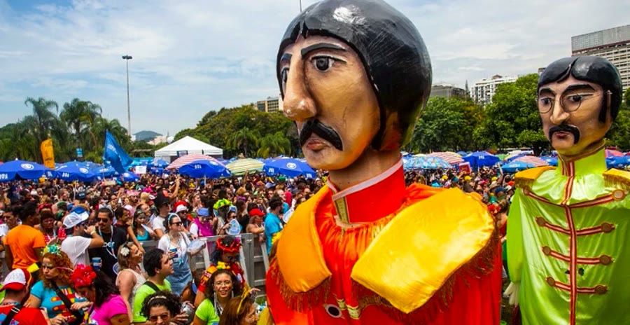 Giant puppet figures towering over a bloco street party crowd