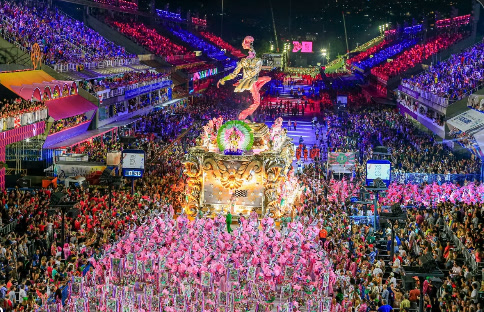 Aerial view of a samba school float and pink-costumed dancers in the Sambadrome at night