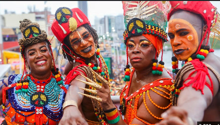 Four performers in beaded costumes and face paint celebrating Carnival